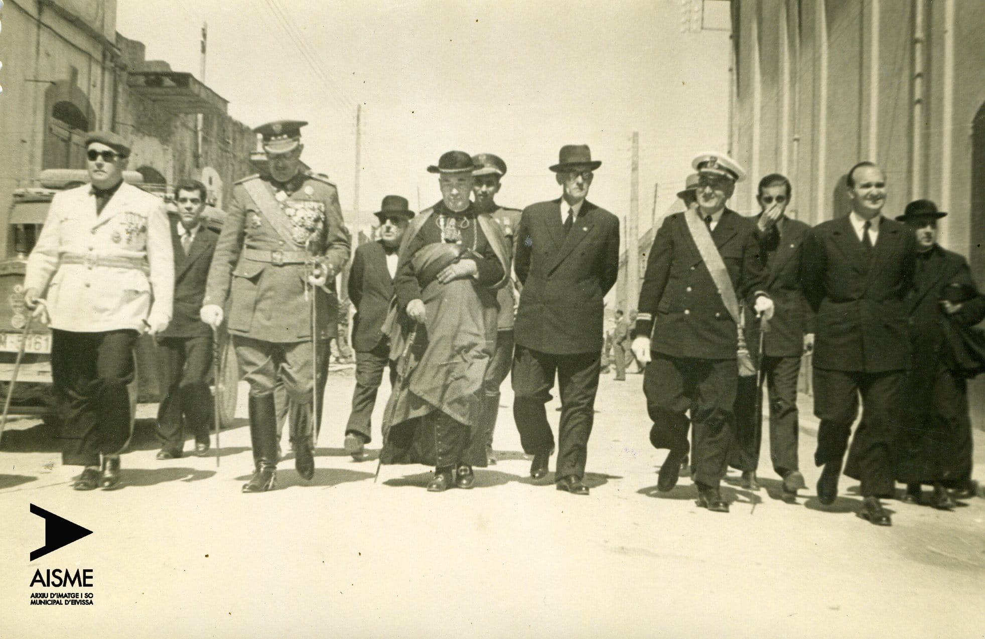 Fotografia en blanc i negre d'una celebració del Día de la Victoria. D’esquerra a dreta, l'alcalde d'Eivissa, Cèsar Puget Riquer, el general Gotarredona i al centre el bisbe Cardona Riera, bisbe Frit.